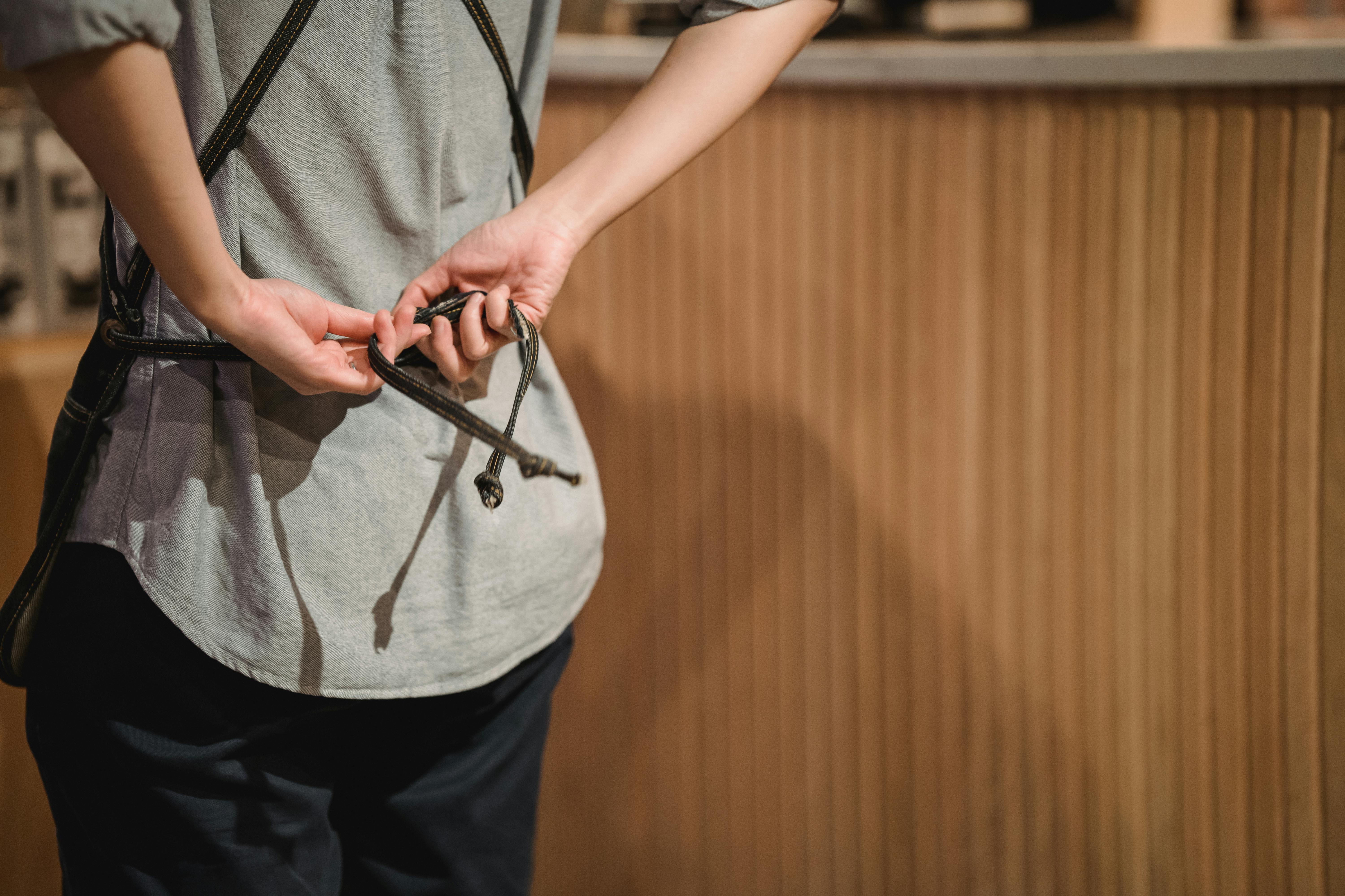 Eine Person bindet sich die Schürze auf dem Rücken - Minijob und Feiertage